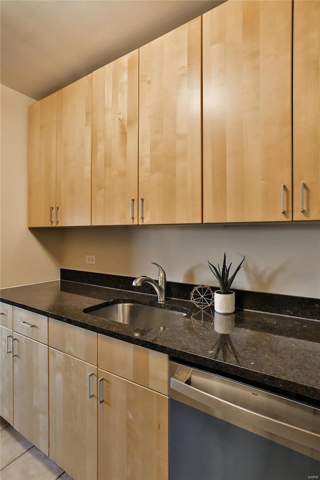 kitchen featuring dishwasher, light brown cabinets, dark stone countertops, and sink