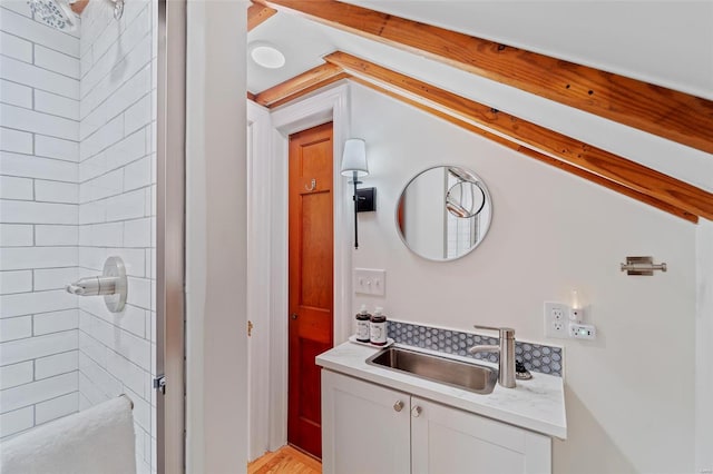 bathroom with a tile shower and vanity