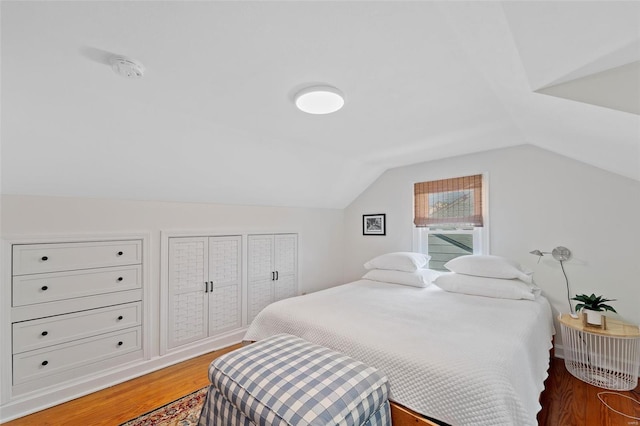 bedroom featuring dark wood-type flooring and vaulted ceiling