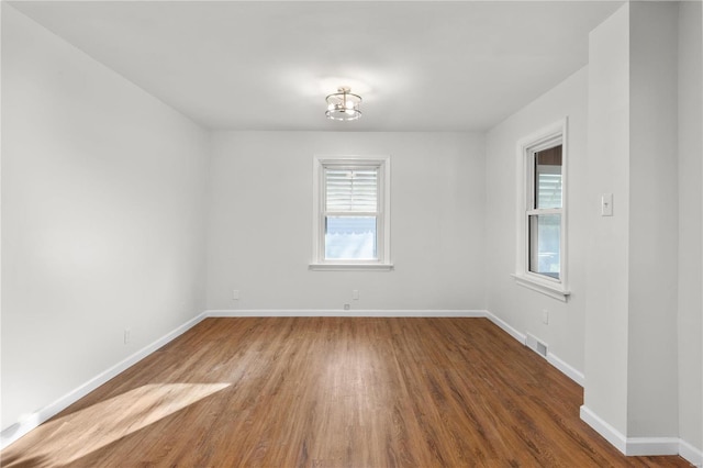 empty room featuring dark wood-type flooring and a healthy amount of sunlight