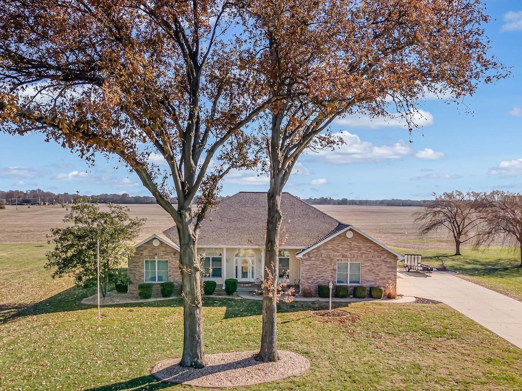 ranch-style house featuring a rural view and a front lawn