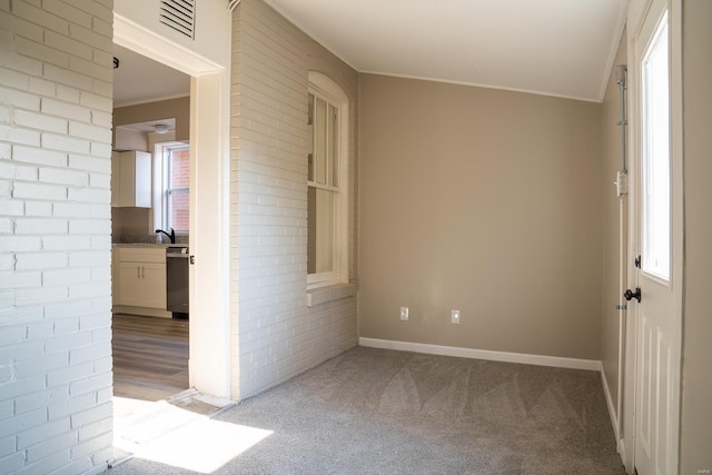 unfurnished room with light colored carpet, ornamental molding, and a wealth of natural light