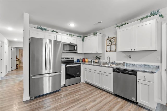 kitchen featuring white cabinets, sink, appliances with stainless steel finishes, light hardwood / wood-style floors, and light stone counters