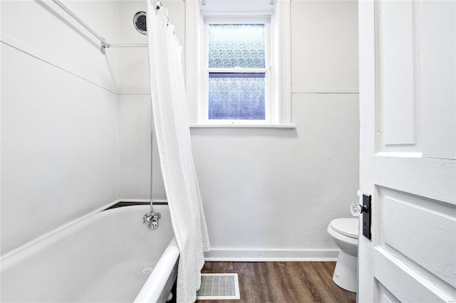 bathroom with toilet, wood finished floors, visible vents, baseboards, and shower / bath combo with shower curtain