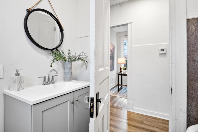 bathroom with wood finished floors, vanity, and baseboards