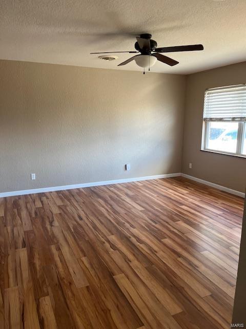 unfurnished room with wood-type flooring and a textured ceiling