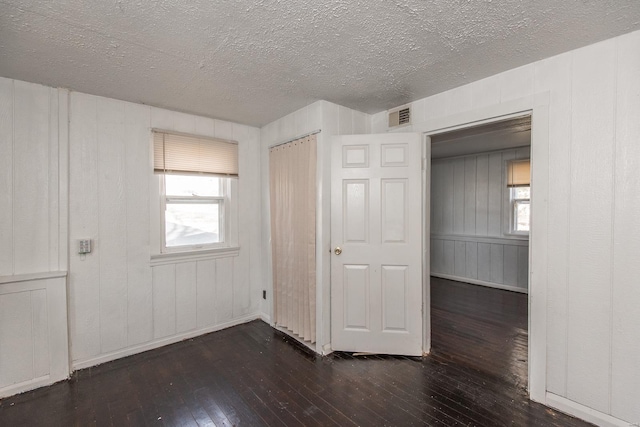 unfurnished bedroom with a textured ceiling and dark hardwood / wood-style floors