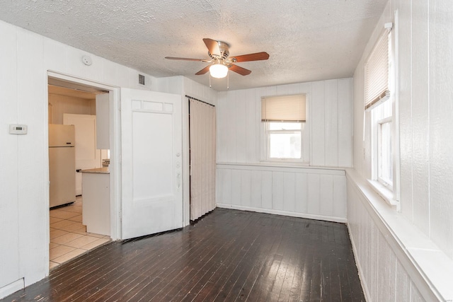 unfurnished bedroom featuring hardwood / wood-style floors, white refrigerator, and multiple windows