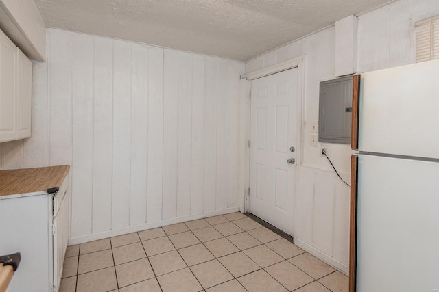 kitchen featuring white cabinetry, electric panel, white fridge, a textured ceiling, and wooden walls