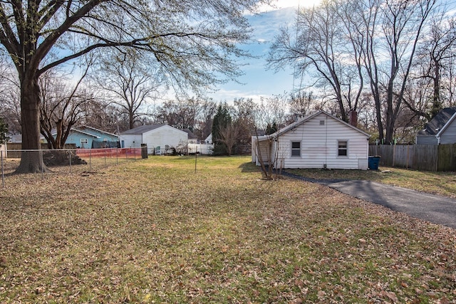 view of yard with fence and aphalt driveway