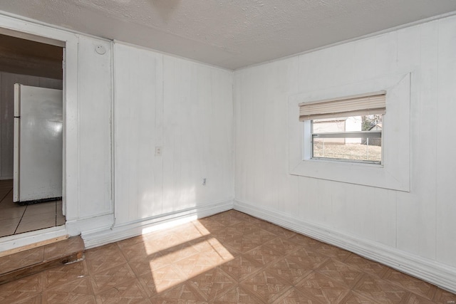 empty room featuring a textured ceiling and baseboards