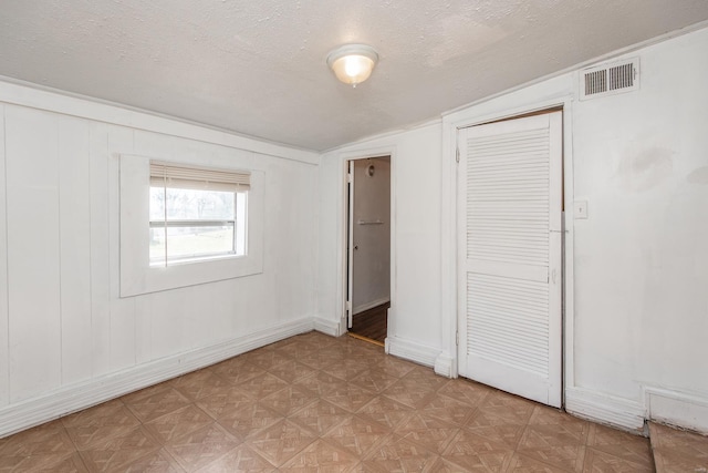 unfurnished bedroom with visible vents, vaulted ceiling, a textured ceiling, light floors, and a closet