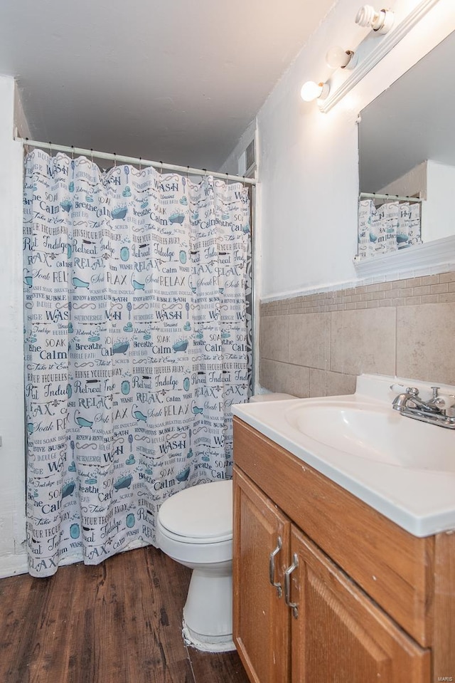 full bath featuring wainscoting, toilet, wood finished floors, vanity, and tile walls