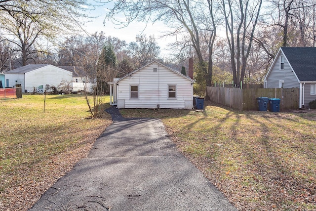 view of home's exterior featuring a chimney, fence, and a yard