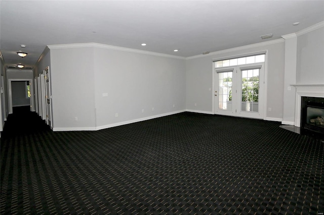 spare room with a fireplace, dark carpet, and crown molding