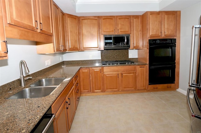 kitchen with appliances with stainless steel finishes, light tile patterned floors, dark stone counters, and sink