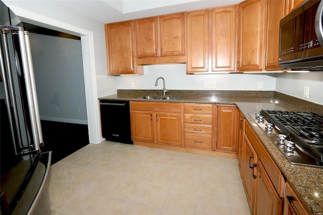 kitchen featuring dark stone countertops, sink, and appliances with stainless steel finishes