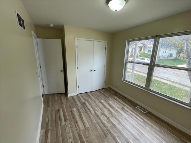 unfurnished bedroom with a closet and light hardwood / wood-style floors