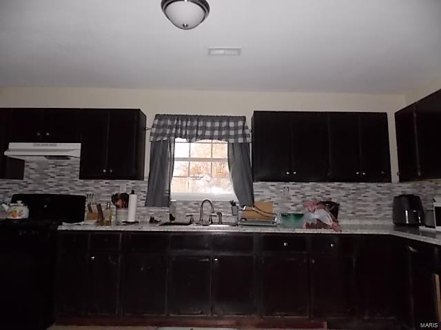 kitchen featuring backsplash, black range, sink, and extractor fan