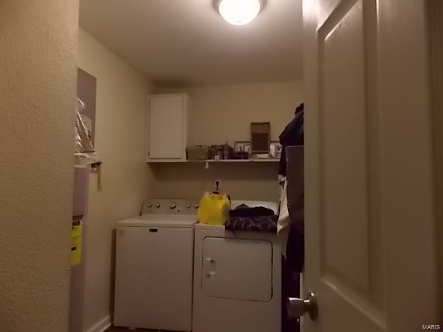 clothes washing area featuring cabinets and washing machine and clothes dryer