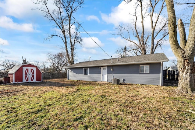 back of house with cooling unit, a yard, and a shed