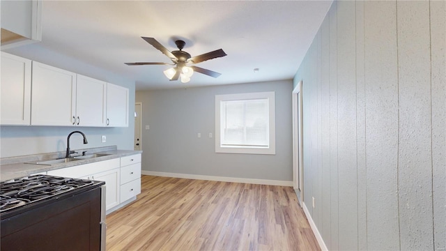 kitchen featuring sink, ceiling fan, light hardwood / wood-style floors, gas stove, and white cabinets