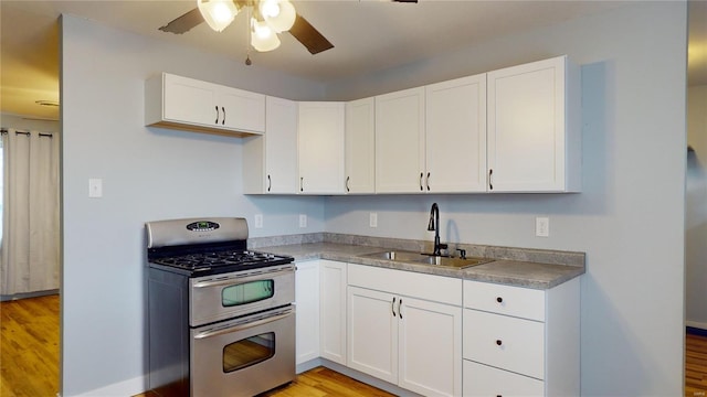 kitchen with light hardwood / wood-style floors, sink, range with two ovens, and white cabinets