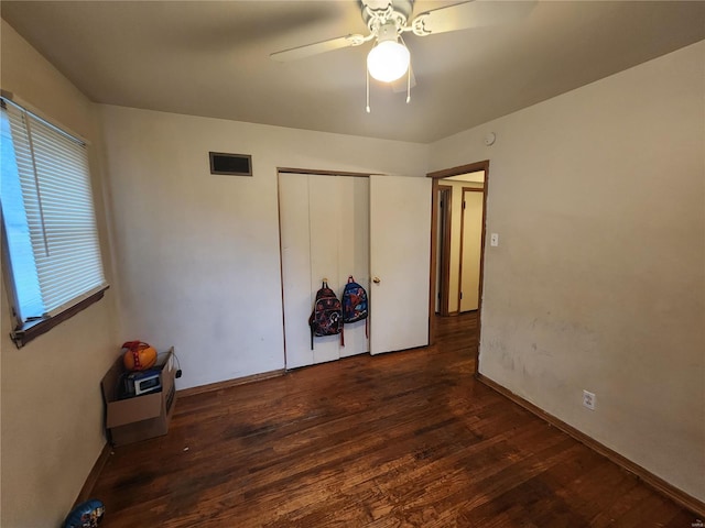 unfurnished bedroom with dark wood-type flooring, ceiling fan, and a closet