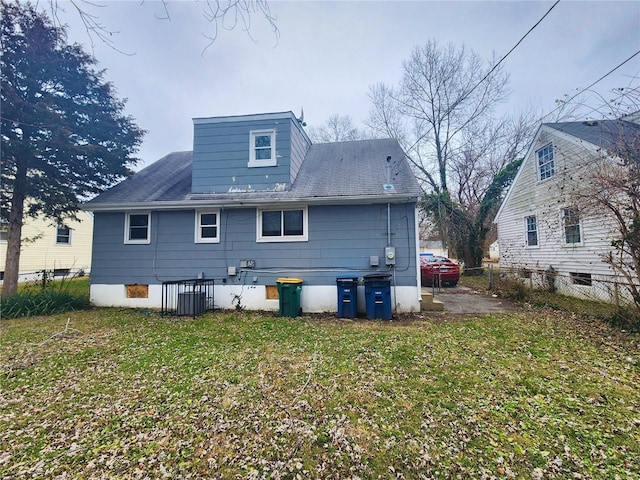 rear view of house with central AC and a lawn