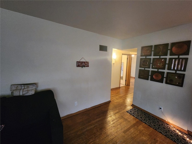 unfurnished room with wood finished floors, visible vents, and baseboards