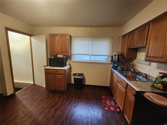 kitchen with black appliances, dark wood finished floors, brown cabinets, and a sink