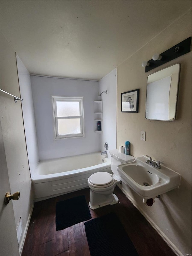 full bath featuring toilet, washtub / shower combination, a sink, and wood finished floors