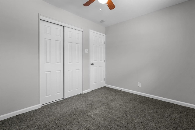 unfurnished bedroom with ceiling fan, a closet, and dark colored carpet