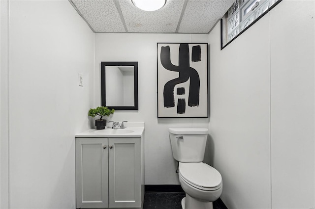 bathroom with a paneled ceiling, vanity, and toilet