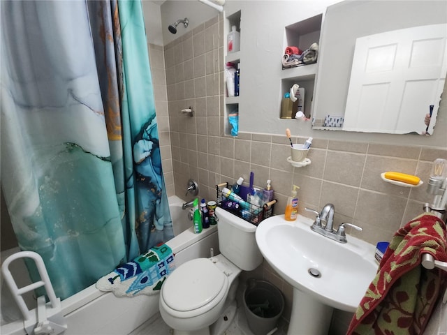 full bath featuring a sink, tile walls, toilet, and shower / bath combo with shower curtain