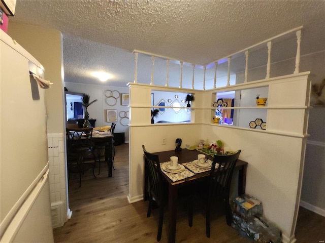 dining space with hardwood / wood-style floors and a textured ceiling