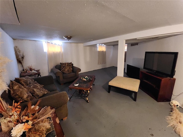 living room with a textured ceiling, visible vents, and concrete flooring