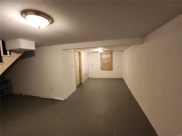 finished basement with a textured ceiling and stairs