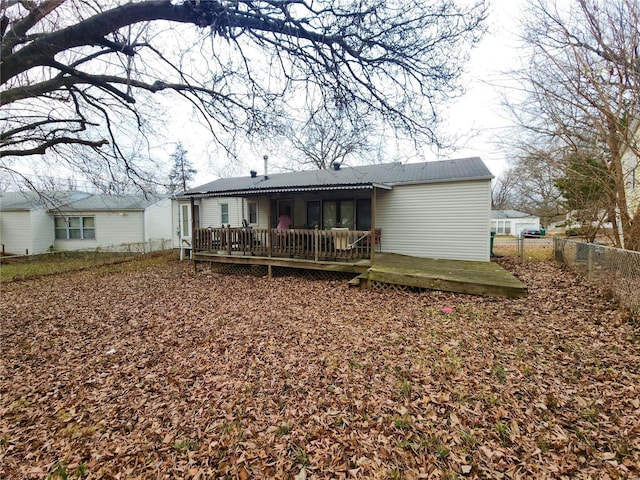 back of property with fence and a wooden deck