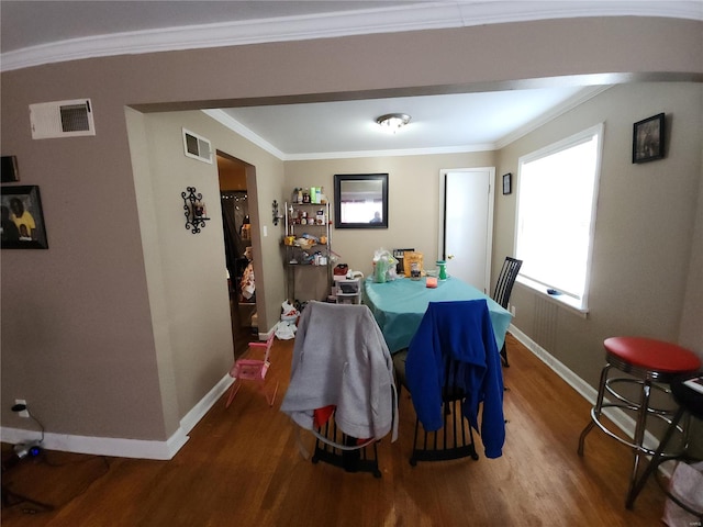 dining room featuring visible vents, arched walkways, wood finished floors, and ornamental molding