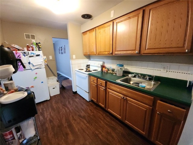 kitchen featuring white appliances, dark wood-type flooring, a sink, visible vents, and dark countertops