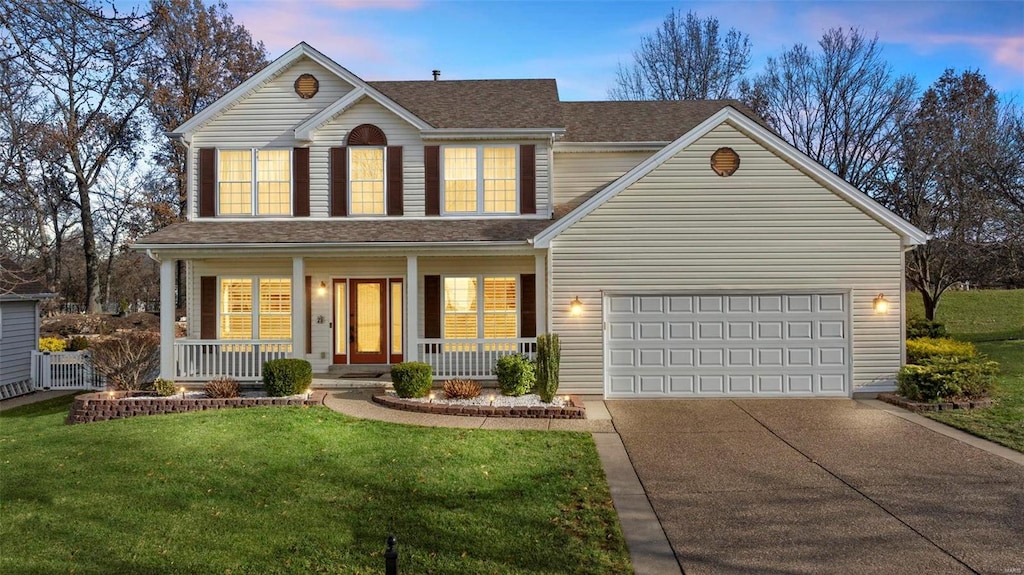 front facade featuring a yard, covered porch, and a garage