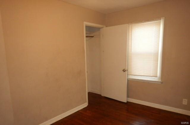 unfurnished bedroom featuring multiple windows, a closet, and dark hardwood / wood-style floors