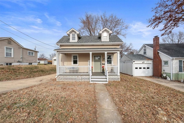 view of front facade featuring covered porch, a garage, and an outbuilding