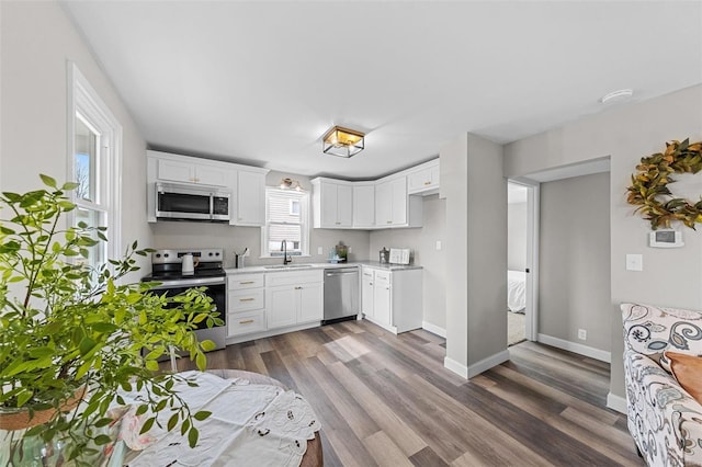 kitchen featuring dark hardwood / wood-style flooring, sink, white cabinets, and appliances with stainless steel finishes