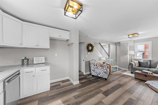 kitchen featuring light stone countertops, white cabinetry, dark wood-type flooring, and stainless steel dishwasher