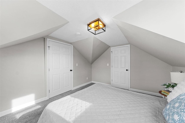 carpeted bedroom featuring a textured ceiling and vaulted ceiling