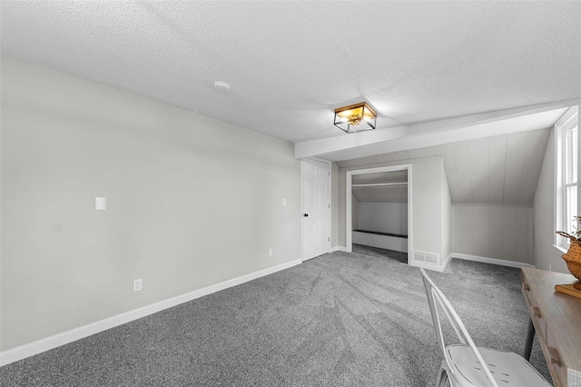 interior space featuring a textured ceiling, a closet, carpet, and lofted ceiling