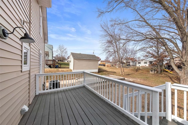 wooden deck featuring a lawn and an outbuilding