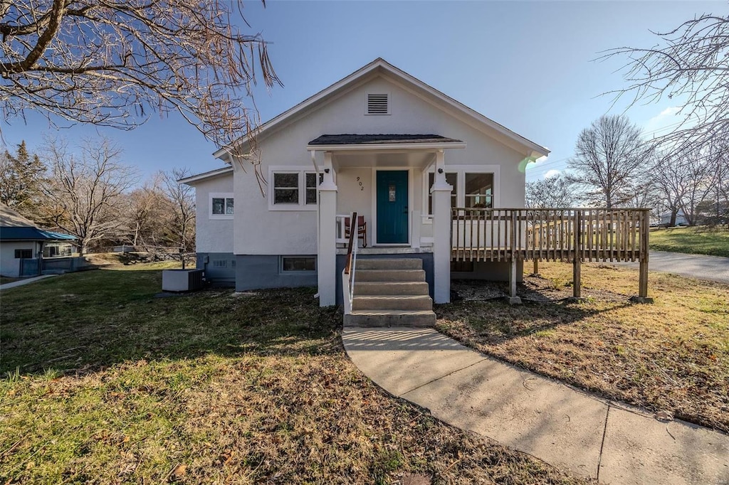 bungalow-style house featuring central AC unit, a deck, and a front yard